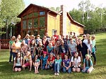 A girls' camp group poses for a photo outside our Red Creek Lodge.