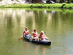 Three girls guide their canoe across the lake.
