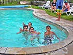Four children playing in the pool, stop to wave at the camera.