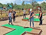 Several girls spend free-time putting at the mini-golf course.