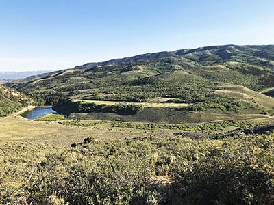 From high up on the mountainside one can view Reid Ranch's lake and plateau with facilities and activities ant-like in the distance.