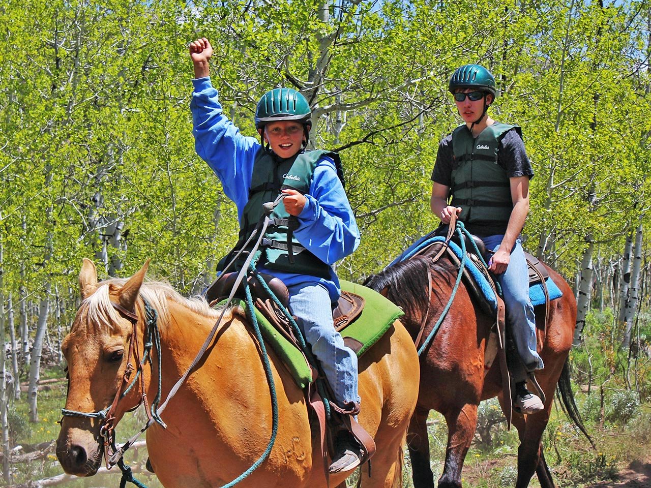 a group of people horseback riding through the Utah mountains
