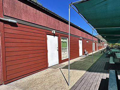 Exterior view of the bunkhouse building showing a little bit of the deck with tables in front.