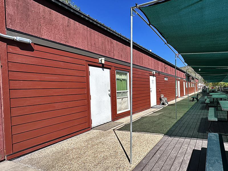 Exterior view of the bunkhouse building showing a little bit of the deck with tables in front.