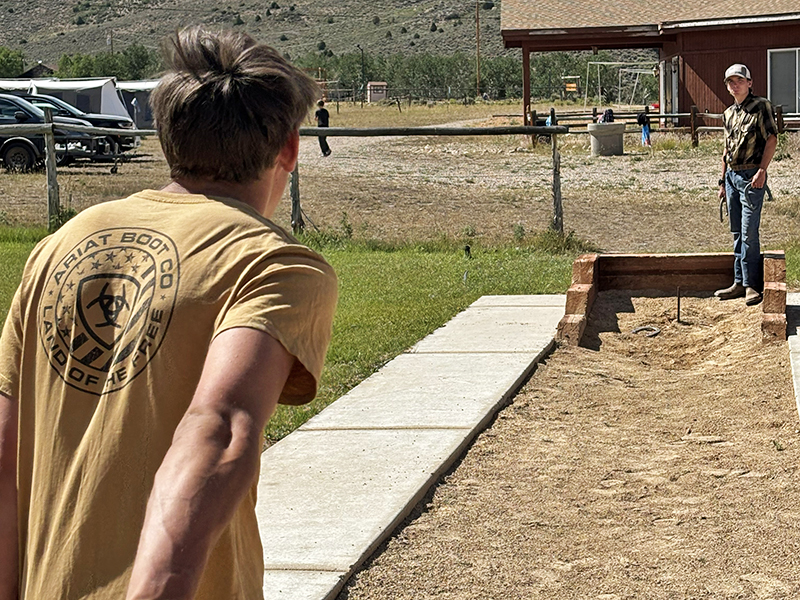 The opponent takes his turn swinging back for a pitch toward the stake on the other side of the court.